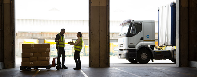 Twee mensen praten bij in loods bij vrachtwagen Twee mensen praten bij in loods bij vrachtwagen