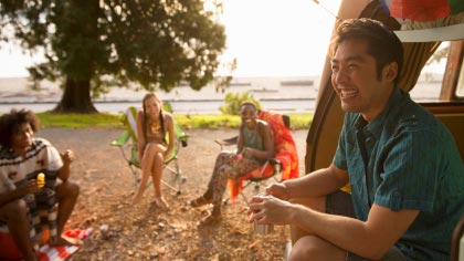 Lachende man zit met vrienden bij camper