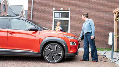 Vrouw met dochter laadt elektrische auto op