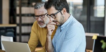 Een man en vrouw zitten samen achter een computer en kijken op een scherm Een man en vrouw zitten samen achter een computer en kijken op een scherm