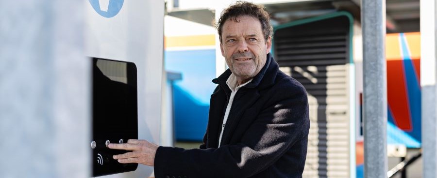 Afbeelding van een man die glimlacht. En bedient een laadstation voor elektrische voertuigen.  Afbeelding van een man die glimlacht. En bedient een laadstation voor elektrische voertuigen.