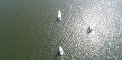 3 witte zeilbootjes varen bij elkaar in de buurt en proberen om schade te voorkomen