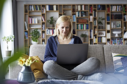 Vrouw zit op de bank met laptop op schoot Vrouw zit op de bank met laptop op schoot